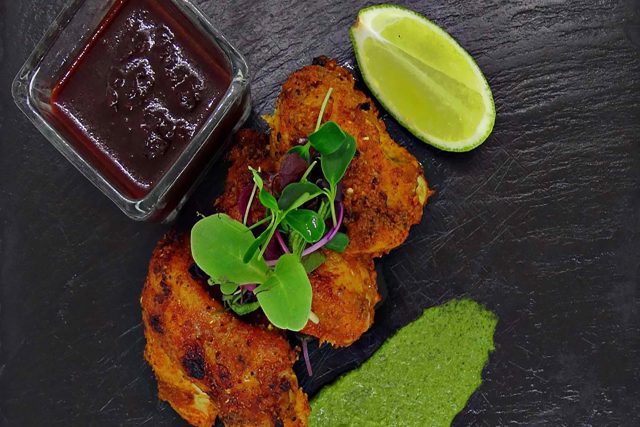 A slate platter featuring vibrant chicken tikka garnished with micro herbs and served alongside fresh mint chutney, showcasing a contemporary Indian Sunday roast starter in Petts Wood.