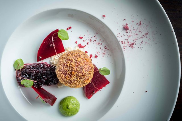 A vibrant serving of crispy vegan beetroot bonda accompanied by fresh chutney, beautifully presented on a contemporary plate at our Petts Wood restaurant.