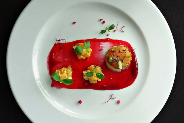 A perfectly seared scallop presented with vibrant red chutney and mango relish, illustrating the contemporary fine dining dishes available on the Thali menus at our Petts Wood restaurant.
