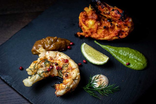 A vibrant platter of tandoori grilled prawns served with fresh green chutney, showcasing the festive contemporary Indian dishes at our Petts Wood restaurant.