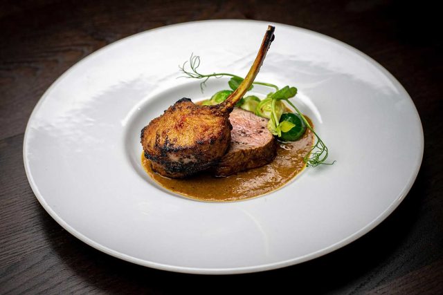 A premium glass of red wine paired elegantly with perfectly tandoori-grilled lamb chops, showcasing the exceptional dining experience at our Petts Wood restaurant.