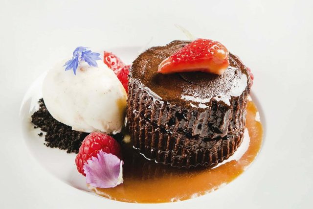 A warm, rich chocolate lava cake served with salted caramel ice cream, showcasing the contemporary Indian desserts available on our Petts Wood set dinner menu.