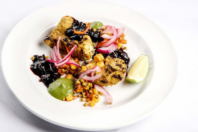 Succulent tandoori grilled chicken tikka elegantly plated with a rich berry chutney and pickled onions, highlighting traditional Indian cooking techniques at our Petts Wood restaurant.