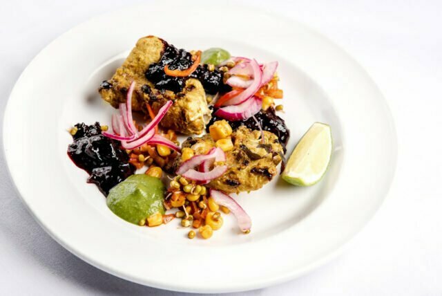 Succulent tandoori grilled chicken tikka elegantly plated with a rich berry chutney and pickled onions, highlighting traditional Indian cooking techniques at our Petts Wood restaurant.