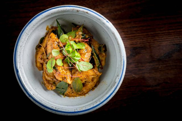 A warmly spiced chicken curry elegantly finished with a delicate microgreens garnish, showcasing the contemporary Indian culinary techniques taught in our Petts Wood masterclass.
