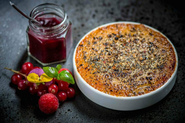 A delicately spiced crème brûlée served with fresh berry compote, reflecting the contemporary Indian desserts crafted by Chef Atul Kochhar.