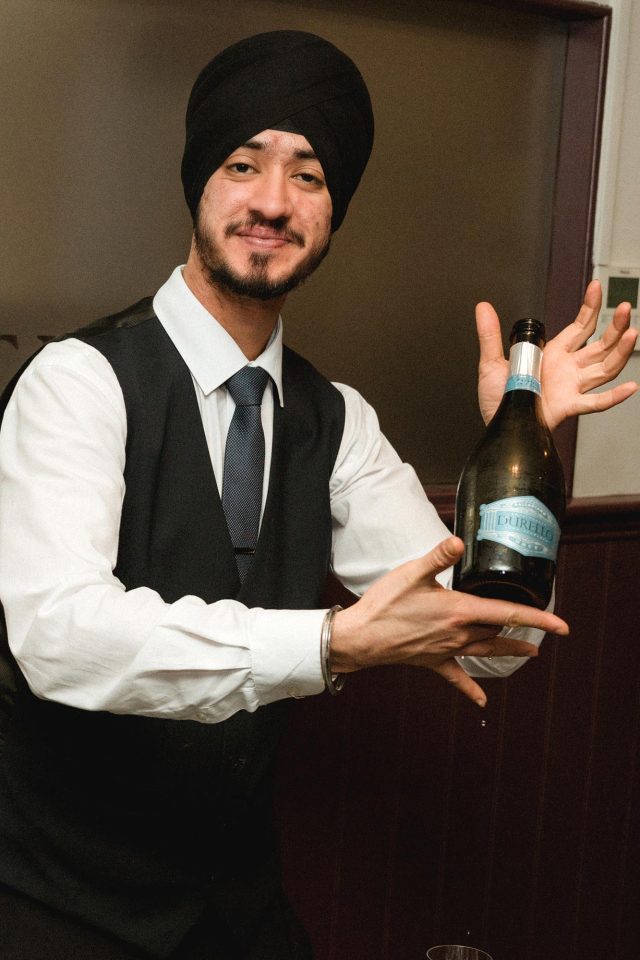 Professional server pouring a glass of fine wine for guests in the dining room at Indian Essence in Petts Wood.