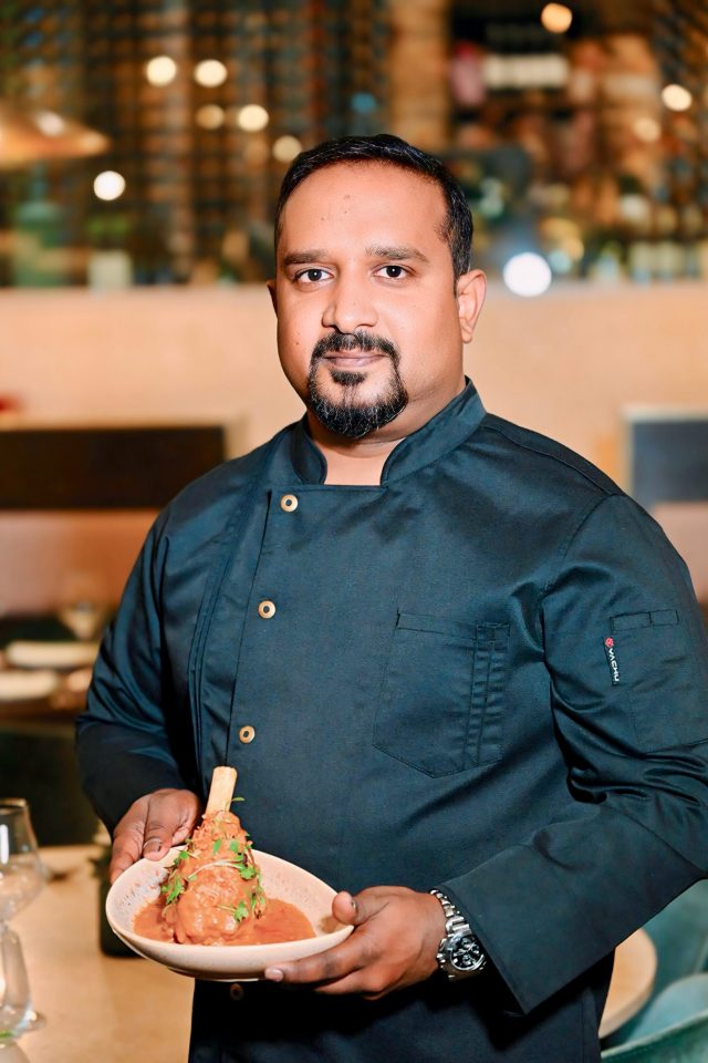 Chef carefully plating a slow cooked lamb shank dish for the exclusive Four Hands tasting menu at Indian Essence in Petts Wood.