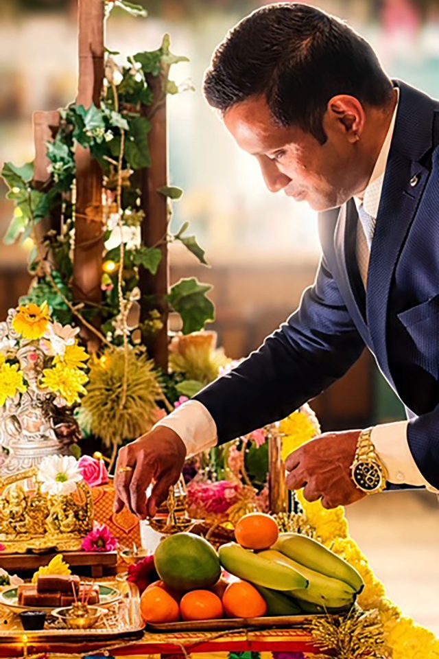 Performing a traditional Diwali puja ceremony with fresh fruits, flowers, and an oil lamp at Indian Essence restaurant.